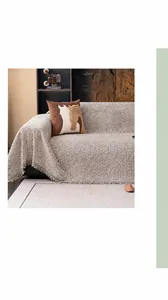 Detail view of beige linen-textured sofa cover with fine decorative fringe edges