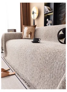 Détail du tissu en lin beige tissé épais et des franges de cette housse de canapé élégante