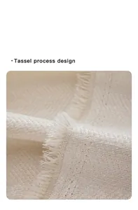Detalle de funda de sofá de chenilla crema con bordes de borlas y textura de espiga fina