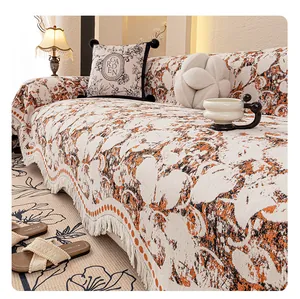 Detailed close-up of chenille sofa cover showing orange floral patterns and fringe edges
