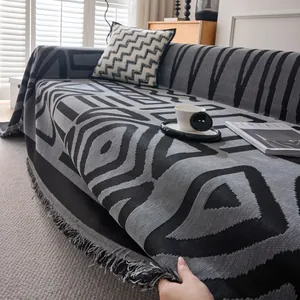 Gray bohemian sofa throw cover with geometric patterns and fringe edges on a couch