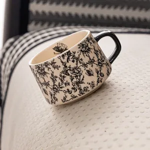 Taza de cerámica retro francesa con flores y asa negra sobre tela beige texturizada