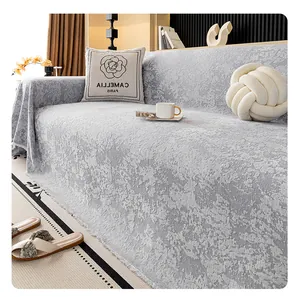 Detail view of grey chenille sofa cover showing embossed jacquard texture and tassel fringe