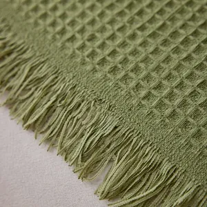Solid green waffle weave chenille sofa cover with soft texture and decorative fringe edge