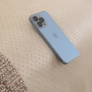 Smartphone azul claro minimalista con triple cámara sobre sofá de tela con textura