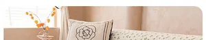 Detail of white quilted cushion with black floral embroidery on chenille sofa cover