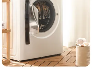 Detail of a white front-load washing machine with a wooden shelf and cozy home decor