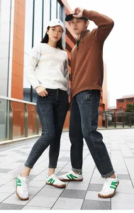 Full body shot of couple wearing retro sneakers with white sweatshirts and denim pants
