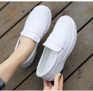 White leather nursing loafers with cushioned soles shown on a dark wood floor
