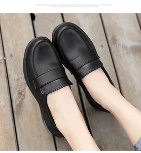 Close-up of black leather flat loafers with round toe on a warm wooden floor
