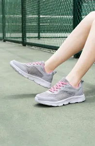Dettaglio di sneaker in rete grigia con lacci rosa su un campo da tennis