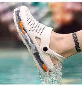 Nahaufnahme wasserfester Clogs mit Camouflage-Sohle beim Spritzen durch das Wasser