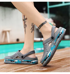 Nahaufnahme grauer Herren-Clogs mit Camo-Sohle auf einem Pooldeck aus Holz