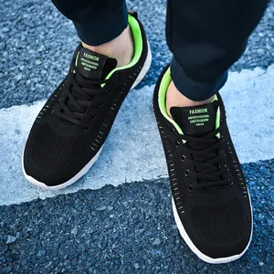 Close-up of black breathable mesh sneaker with neon green accents on a street pavement