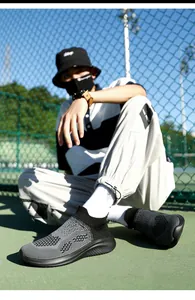 Close-up of men's breathable knit running shoe in grey and black on a green tennis court
