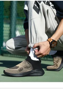 Close-up of beige and black knit sneakers with textured sole on a green sports track