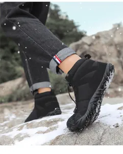 Close-up of black high-top snow boots with non-slip rubber soles on snowy rocks