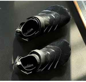 Détail de chaussures pieds nus noires avec fermeture à scratch et rayures blanches