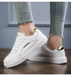 Close-up of white casual sneakers featuring gold metallic accents on a platform sole