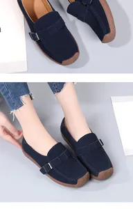 Detail von dunkelblauen Wildleder-Loafers mit Metallschnallen und braunen Gummisohlen