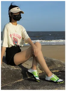 Détail de chaussures aquatiques blanches à rayures vertes et laçage rapide sur plage