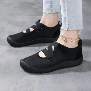Black barefoot water shoes with cross straps and non-slip rubber sole on marble floor