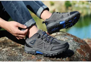 Nahaufnahme robuster grauer Wanderschuhe mit verstärkter Kappe auf rauen Bergfelsen