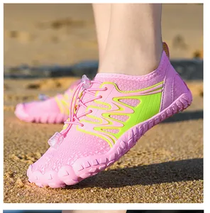 Detail of pink wading shoes with quick-lace system and grippy soles on beach sand