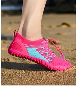 Detail view of pink quick-dry water shoes with non-slip rubber soles on beach sand