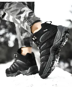 Close-up of black hiking boots with suede upper and anti-slip thick rubber soles on snow