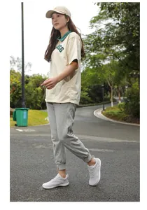 Outdoor lifestyle view of women's beige polo shirt and grey joggers set with ASG logo