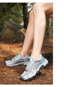 Close-up of grey and blue women's hiking shoes with rugged grip soles on pine forest ground