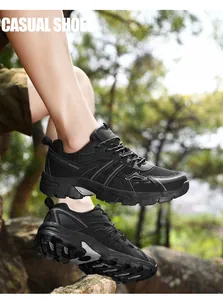 Black outdoor hiking sneakers with non-slip soles on a rocky forest background