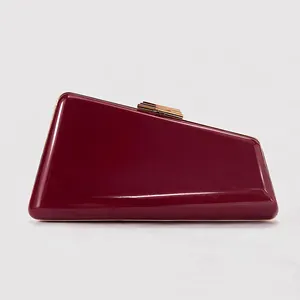 Detail of burgundy snakeskin PU evening clutch with asymmetric geometric shape and gold clasp