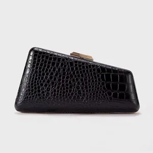 Macro detail of glossy black crocodile embossed faux leather and golden buckle clasp