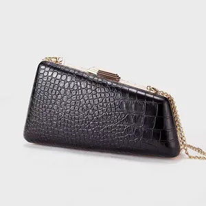 Macro shot of black faux-crocodile leather texture and gold metal chain on evening bag