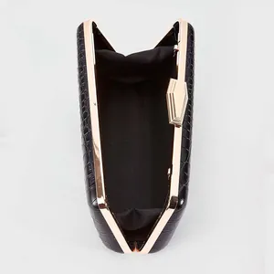 Detail view of black crocodile pattern evening clutch with gold metal frame and hardware