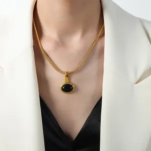 Détail d'un pendentif ovale noir vintage sur une chaîne serpent dorée en acier titane