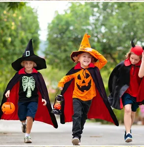 Three children in red and black Halloween cloaks running through an outdoor forest trail