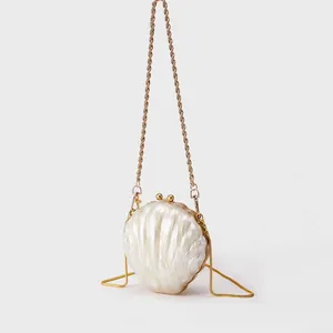 Vue détaillée de la pochette coquillage en acrylique nacré avec cadre doré et fermoir boule