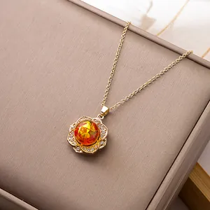 Close-up of a floral pendant with orange sphere stone and cubic zirconia inlay