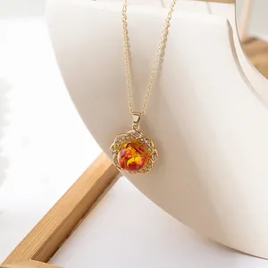 Macro shot of a golden floral pendant necklace with a red resin core and zircon petals