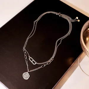 Detail of silver layered necklace with H-shaped buckle and elephant coin pendant