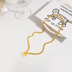 Detail of gold snake chain necklace with a transparent floral pendant and yellow core