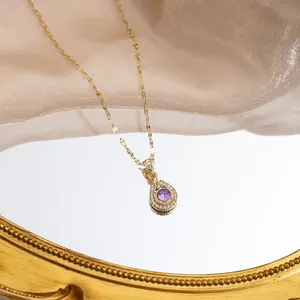 Macro detail of golden teardrop pendant with purple center stone and white crystals