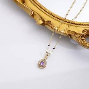Detail of gold teardrop pendant with purple gemstone and crystals on vintage mirror