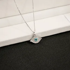 Macro shot of a silver evil eye pendant with blue crystals on a thin necklace chain