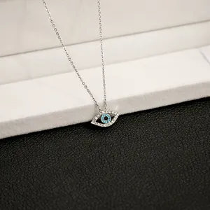 Detailed macro view of silver evil eye pendant with blue crystals on a jewelry stand