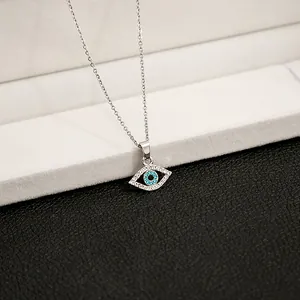 Detailed view of silver evil eye pendant with clear crystals and blue center on fine chain
