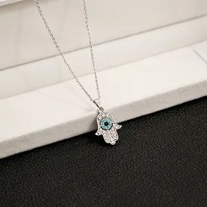 Macro shot of silver Hamsa Hand necklace with blue evil eye and sparkling rhinestones